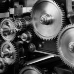 Close-up view of a complex industrial gear mechanism in black and white.