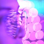 Close-up photo of eyeglasses with bright purple and blue bokeh lights creating an abstract aesthetic.