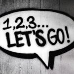 Black and white street art featuring a bold motivational message in a speech bubble.